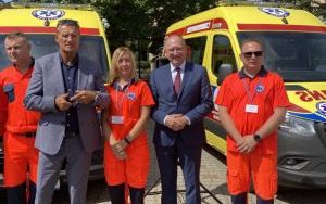 Trzech ratowników medycznych oraz przedstawiciel wojewody wraz z dyrektorem szpitala na tle dwóch ambulansów