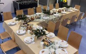 Stół wigilijny z obrusem, talerzami i dekoracjami świątecznymi